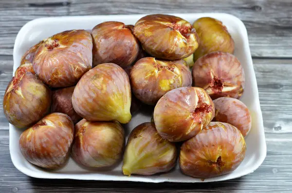 A plate of figs parchment fruit isolated on wooden background, fig is the edible fruit of Ficus carica, a species of small tree in the flowering plant family Moraceae, selective focus