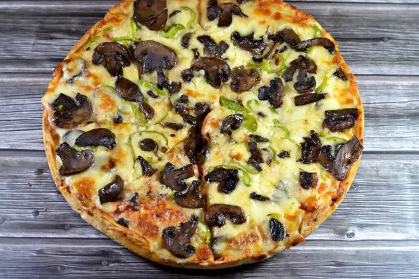 Siyah mantar dilimli mantar pizzası, zeytin, sebze, mozarella peyniri, zeytin yağı ve taze otlar, yüksek kenarlı yuvarlak, fırında pişirilmiş, seçici odaklı