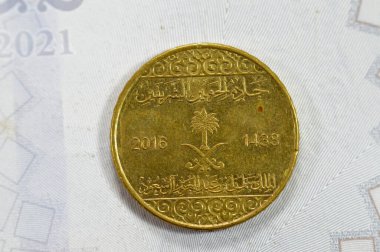 A quarter of SAR Saudi Arabian riyal coin 25 Halalas, features Coat Of Arms Two crossed swords and Palm Tree, Name of King Salman Bin AbdulAziz on the obverse, Trefoil Floral Ornamentation on reverse clipart