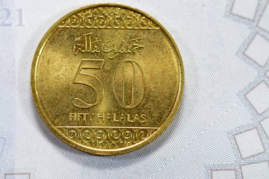 Half riyal golden coin 50 fifty Halalas, features trefoil floral ornamentation on the top and bottom and the arms of Saudi Arabia in the center with two crossed swords and palm tree on obverse side clipart