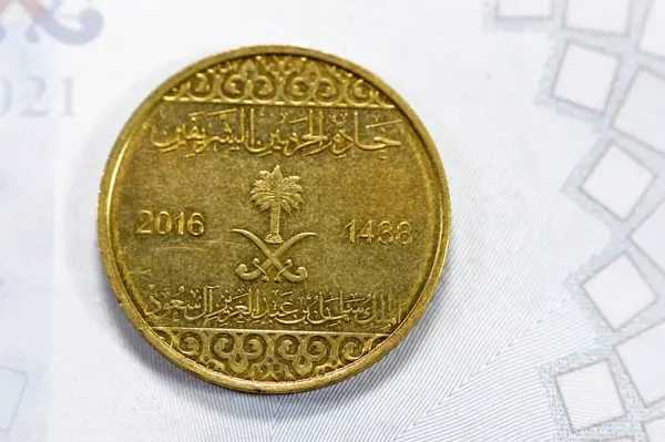 stock image Half riyal golden coin 50 fifty Halalas, features trefoil floral ornamentation on the top and bottom and the arms of Saudi Arabia in the center with two crossed swords and palm tree on obverse side