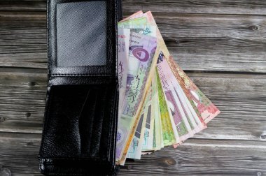 Suudi Arabistan Riyals faturaları banknotlar, siyah deri bir cüzdanda SAR riyal nakit para yığını, satın alma, satış, para ve ekonomik durum, büyüme ve enflasyon kavramları
