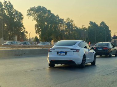 Giza, Mısır, 9 Ağustos 2024: Yoldaki beyaz Tesla arabası, Tesla, merkezi Austin, Teksas 'ta bulunan çok uluslu bir otomobil ve temiz enerji şirketidir.