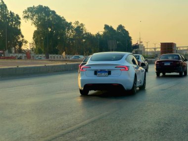 Giza, Mısır, 9 Ağustos 2024: Yoldaki beyaz Tesla arabası, Tesla, merkezi Austin, Teksas 'ta bulunan çok uluslu bir otomobil ve temiz enerji şirketidir.