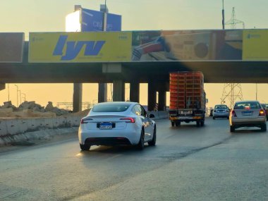 Giza, Mısır, 9 Ağustos 2024: Yoldaki beyaz Tesla arabası, Tesla, merkezi Austin, Teksas 'ta bulunan çok uluslu bir otomobil ve temiz enerji şirketidir.