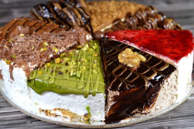 Süngerimsi kek parçaları çeşitli malzemelerle doldurulmuş krema, çikolata ezmesi, çikolata parçaları ve top çikolatalar, bisküvi sosu ve yapıştırıcı, karamel, şam fıstığı parçaları ve krema, ceviz