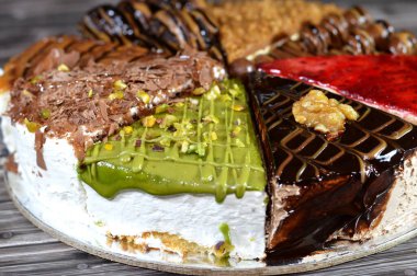 Süngerimsi kek parçaları çeşitli malzemelerle doldurulmuş krema, çikolata ezmesi, çikolata parçaları ve top çikolatalar, bisküvi sosu ve yapıştırıcı, karamel, şam fıstığı parçaları ve krema, ceviz