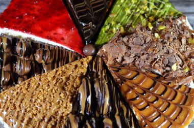 Süngerimsi kek parçaları çeşitli malzemelerle doldurulmuş krema, çikolata ezmesi, çikolata parçaları ve top çikolatalar, bisküvi sosu ve yapıştırıcı, karamel, şam fıstığı parçaları ve krema, ceviz