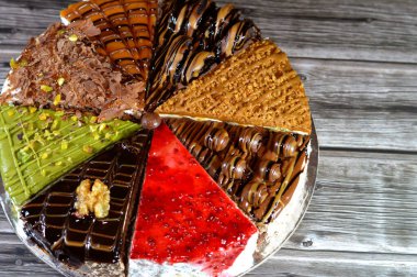 Süngerimsi kek parçaları çeşitli malzemelerle doldurulmuş krema, çikolata ezmesi, çikolata parçaları ve top çikolatalar, bisküvi sosu ve yapıştırıcı, karamel, şam fıstığı parçaları ve krema, ceviz