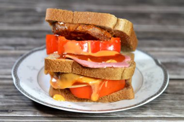 Kızarmış sığır burgeriyle dolu çok katmanlı tam buğday ekmekli tost. Renkli dolma biber dilimleri ve öğle yemeği, öğle yemeği, öğle yemeği, ketçap ve hamburger sosuyla birlikte sığ bir yağda pişirilmiş.