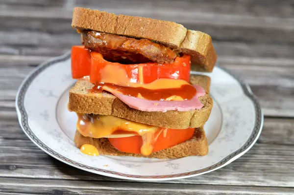 Kızarmış sığır burgeriyle dolu çok katmanlı tam buğday ekmekli tost. Renkli dolma biber dilimleri ve öğle yemeği, öğle yemeği, öğle yemeği, ketçap ve hamburger sosuyla birlikte sığ bir yağda pişirilmiş.