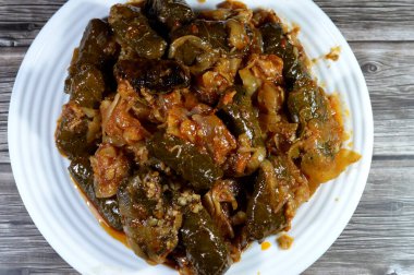 A plate of baked of kawareh trotters collagen and Gelatin, cooked cow feet, boneless trotters and wrapped grape leaves stuffed Egyptian Mahshi and filled with white rice, onion, parsley, dill clipart