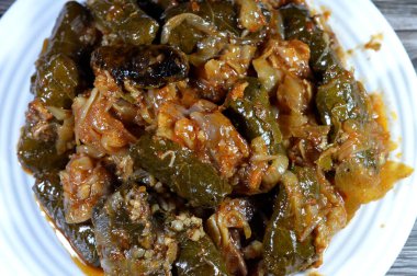 Bir tabak kawareh paça kolajen ve jelatin, pişmiş inek ayağı, kemiksiz paça ve sarılı üzüm yaprağı doldurulmuş Mısır Mahşisi ve içi beyaz pirinç, soğan, maydanoz, dereotla dolu.