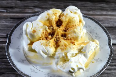 Karamel soslu zengin vanilyalı karamelli dondurma ve üzerine karamelli fındık parçaları, dondurulmuş ve servis edilmeye hazır, yaz zamanı ve tatil konsepti, ferahlatıcı ve eğlenceli, seçici odaklanma.