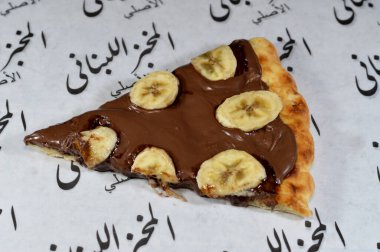 Kahire, Mısır, 13 Kasım 2024: Fındık kremalı ve fırında pişirilmiş taze muz meyveli çikolata ezmeli tatlı pizza Lübnan fırınından fırınlanmış pizza tatlısı
