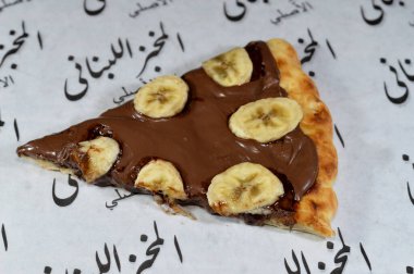 Kahire, Mısır, 13 Kasım 2024: Fındık kremalı ve fırında pişirilmiş taze muz meyveli çikolata ezmeli tatlı pizza Lübnan fırınından fırınlanmış pizza tatlısı