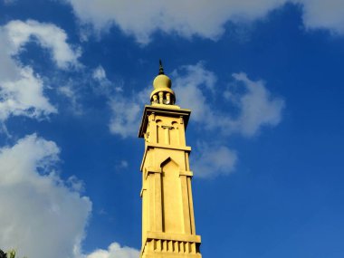 Mavi bulutlu gökyüzü, minare veya kuleye karşı ahşap süslemeli yüksek minare, İslam dini ve mimari konsepti, cami direği, seçici odak noktası