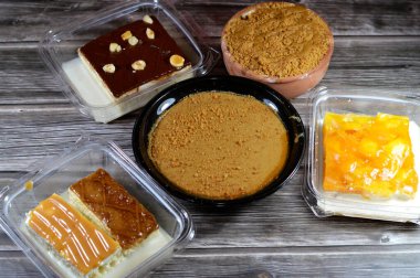 Fırınlanmış Om Ali 'nin çeşitli tatlıları ve üzerine süt ve şeker sürülmüş pirinç pudingi üzerine tereyağı serpiştirilmiş bisküvi, üstüne karamel, çikolata, mango parçaları ve fındıklı Tres lech keki.