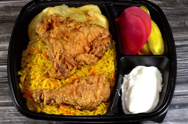 Renkli Basmati pilavlı kızarmış tavuk yemeği, turşu dilimleri, salatalık, şalgam, kızarmış patates cipsi, broş tavuk parçaları, buğulama basıncı ve geleneksel sığ kızartmayı birleştirir.