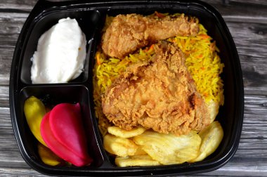 Renkli Basmati pilavlı kızarmış tavuk yemeği, turşu dilimleri, salatalık, şalgam, kızarmış patates cipsi, broş tavuk parçaları, buğulama basıncı ve geleneksel sığ kızartmayı birleştirir.