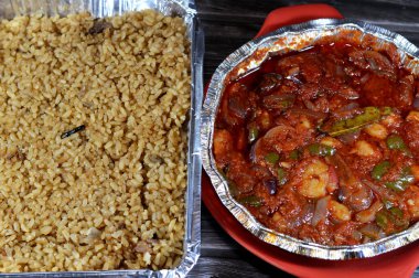 Kırmızı sos, defne, maydanoz, soğan dilimleri ve soğanlı sarımsak, soğanlı kırmızı pirinç balığı, karides ve pilav ile fırında pişirilmiş orta boy kabuklu karides.
