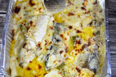 Kremalı beyaz soslu fırınlanmış tekir balıkları, patates parçaları ve dilimleri, ghee, bitkiler ve balık baharatları, fırında pişirilmiş, deniz ürünleri, patatesli tekir balığı mutfağı, iki yarıya bölünmüş balıklar.