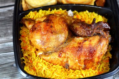 Arabic Syrian cuisine of machine grilled barbecued chicken with colorful Basmati rice and fried thin chips potatoes served in a black disposable plate, usually served with garlic sauce and pickles clipart