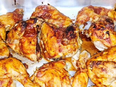 Fırında fırında tavuk parçaları, fırında kemikli tavuk parçaları ve tepside domates ezmesiyle kaplanmış, seçici bir odak noktası.