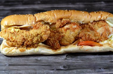 Kızarmış tavuk parçaları füme hindi dilimleri, marul, domates, çedar ve büyük lezzetli sos susamlı uzun bir çörek, batı sandviçi tavuk parçaları, hindi, sebze, sos ile dolu.