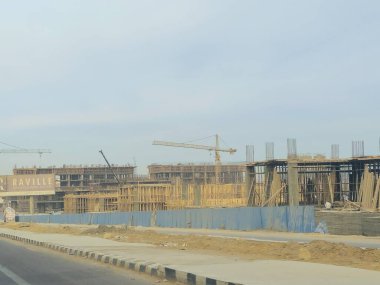 Cairo, Egypt, January 4 2025: A new high rise of residential apartments in new Cairo, New buildings under construction, Egyptian real estate projects, scaffoldings and cranes on a construction site clipart