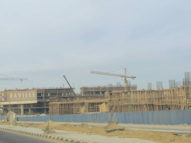 Cairo, Egypt, January 4 2025: A new high rise of residential apartments in new Cairo, New buildings under construction, Egyptian real estate projects, scaffoldings and cranes on a construction site clipart