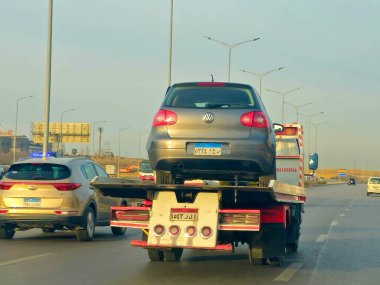 Kahire, Mısır, 19 Ocak 2025: Bir çekici kurtarma taşıyıcısı hidrolik kamyon bozuk bir arabayı yolda hareket ettiriyor, bakım için sokaktan bir arabayı kurtarıyor, seçici odak noktası