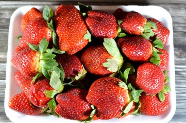 Çilek meyvesi, gül familyasından Fragaria cinsinin yaygın olarak yetişen bir melez türü olan Rosaceae, parlak kırmızı rengi, sulu dokusu ve tatlılığı ile karakterize edilen çilekler, seçici odak noktası.