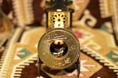 Translation of Arabic text (Happy generous Ramadan Kareem), on an Iftar breakfast cannon and lantern fanous decoration, as a celebration of the fasting month for Muslims, selective focus clipart