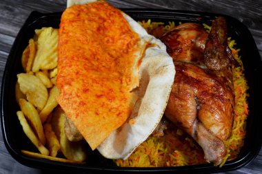 Arap mutfağından ızgara ızgara tavuk rengarenk Basmati pilavı ve kızarmış ince patates genellikle sarımsak sosu ve turşuyla servis edilen tek kullanımlık siyah tabakta servis edilir.