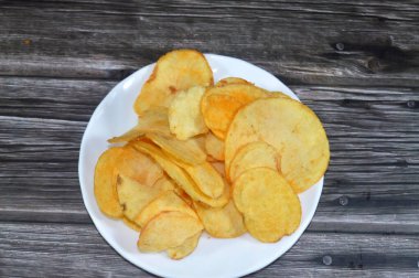 Patates cipsi, cips, ince patates dilimleri, kızartılmış, pişirilmiş, veya kızarana kadar havada kızartılmış, aperatif, meze veya meze olarak servis edilmiş, temel cips pişti ve tuzlandı, bazıları diğer tatlarla birlikte.