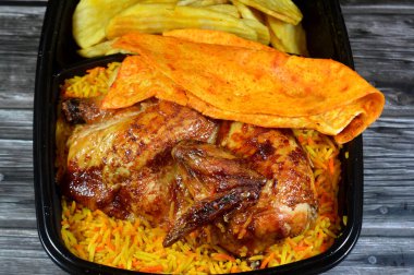 Arabic Syrian cuisine of machine grilled barbecued chicken with colorful Basmati rice and fried thin chips potatoes served in a black disposable plate, usually served with garlic sauce and pickles clipart