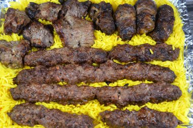 Arabic cuisine traditional food beef  Kofta, kebab and tarb kofta shish which is minced meat with yellow Basmati rice , oriental charcoal grilled barbecued meat food with long yellow rice clipart