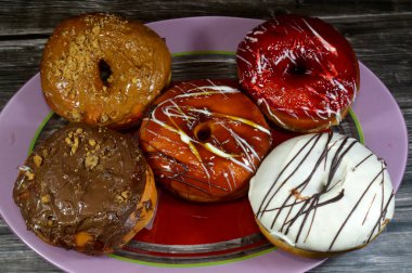 Kahverengi ve beyaz çikolatalı ve karamel, beyaz çikolata soslu çilek ve bisküvi aromalı donutlar, jöleli, maya soslu, Amerikan usulü halka şeklinde donutlar.