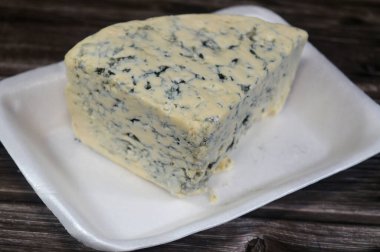 Triangle of a blue cheese, any cheese made with the addition of cultures of edible molds, which create blue-green spots or veins through the cheese, its distinctive smell is from mold or bacteria