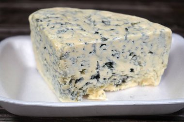 Triangle of a blue cheese, any cheese made with the addition of cultures of edible molds, which create blue-green spots or veins through the cheese, its distinctive smell is from mold or bacteria