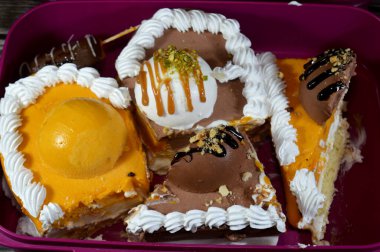 Dondurma ve çeşitli aromalı dondurmalar. Dondurma ve krema içinde kek katmanı olan çeşitli tatlar. Üzerinde karamel sosu olan mango, vanilya ve çikolata.