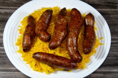 Klasik kızarmış mısır sosisi, içi baharatlı pirinç, otlar, soğan ve domatesle dolu bağırsaklar, uzun sarı Hint Basmati pilavı, seçici odaklı.