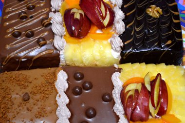 Kutlamalar, koyu çikolata, karamel, bisküvi, çırpılmış vanilya kreması, ananas, şeftali, fındık dilimleri için üç parçadan oluşan dikdörtgen şeklinde doğum günü pastası.