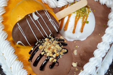 Dondurma ve çeşitli aromalı dondurmalar. Dondurma ve krema içinde kek katmanı olan çeşitli tatlar. Üzerinde karamel sosu olan mango, vanilya ve çikolata.