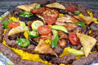 Arap mutfağı geleneksel yemek kömürü ızgara biftek kebap et parçaları, sosis, biftek Kofta, Kufta şiş, ızgara tavuk, sarı Basmati pilavı, domates, salatalık ve biber dilimleri.