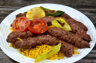 Geleneksel yiyecek bifteği Kofta, közlenmiş et kömürü, ızgara ve ızgara Arap yemeği, sarı Basmati Hint uzun tahıllı pilavı, domates, salatalık ve biber dilimleri ile servis edilir.