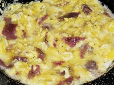 Scrambled eggs with pastrami, a dish made from eggs stirred, whipped or beaten together while being gently heated, with salt, butter, oil and black pepper with slices and pieces of beef pastrami