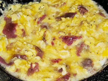 Scrambled eggs with pastrami, a dish made from eggs stirred, whipped or beaten together while being gently heated, with salt, butter, oil and black pepper with slices and pieces of beef pastrami