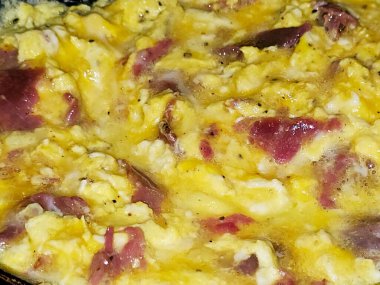 Scrambled eggs with pastrami, a dish made from eggs stirred, whipped or beaten together while being gently heated, with salt, butter, oil and black pepper with slices and pieces of beef pastrami